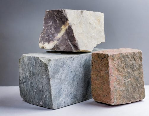 Three blocks of uncut granite of different colours and sizes with